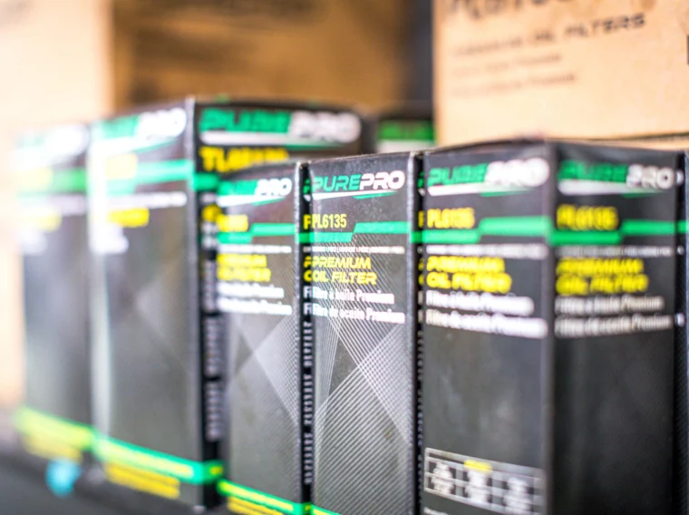 Several PurePro premium oil filter boxes are lined up on a store shelf, highlighting their product labels and part numbers—ideal for those seeking quality filter services.